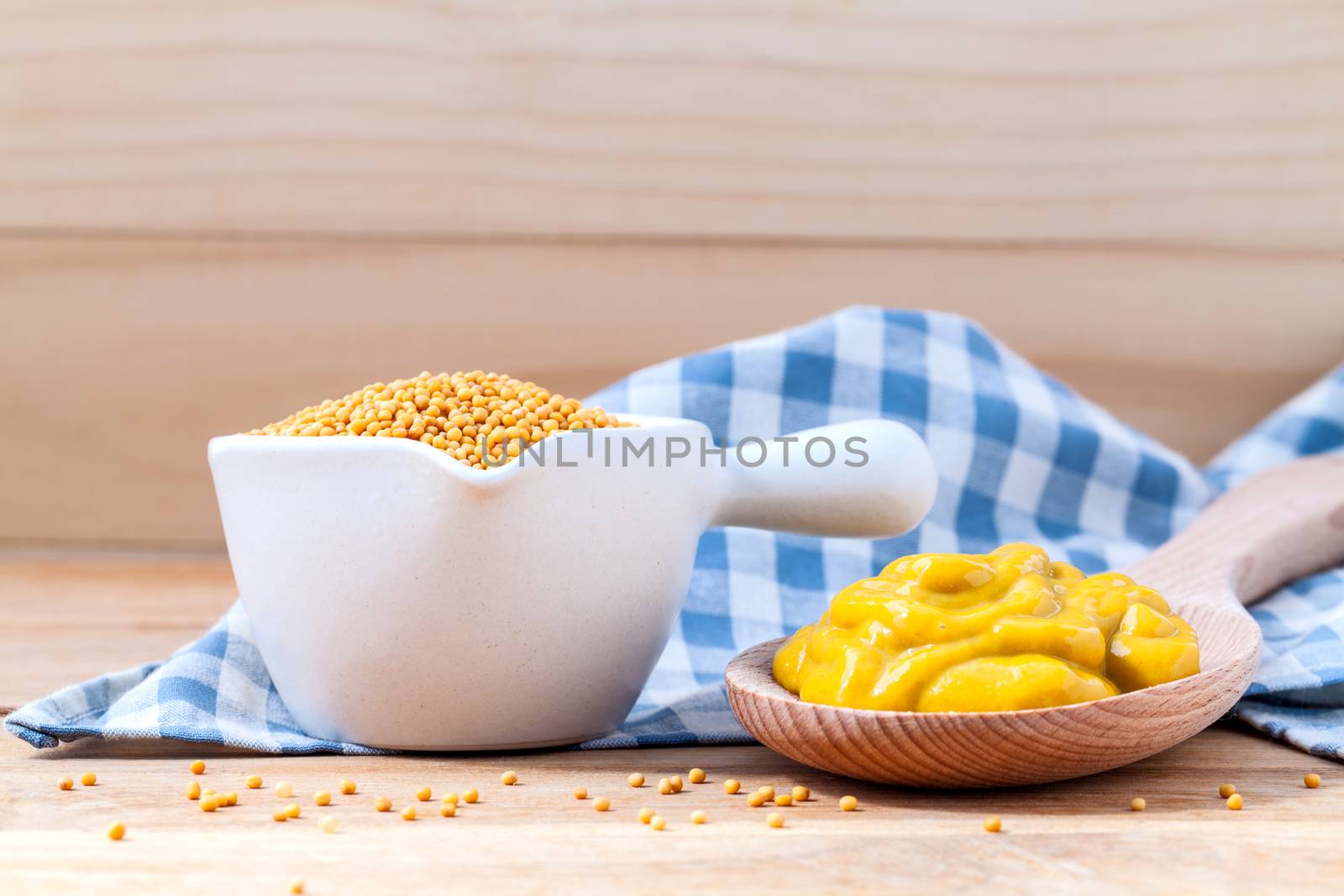 Composition of mustard and mustard seeds on wooden background.