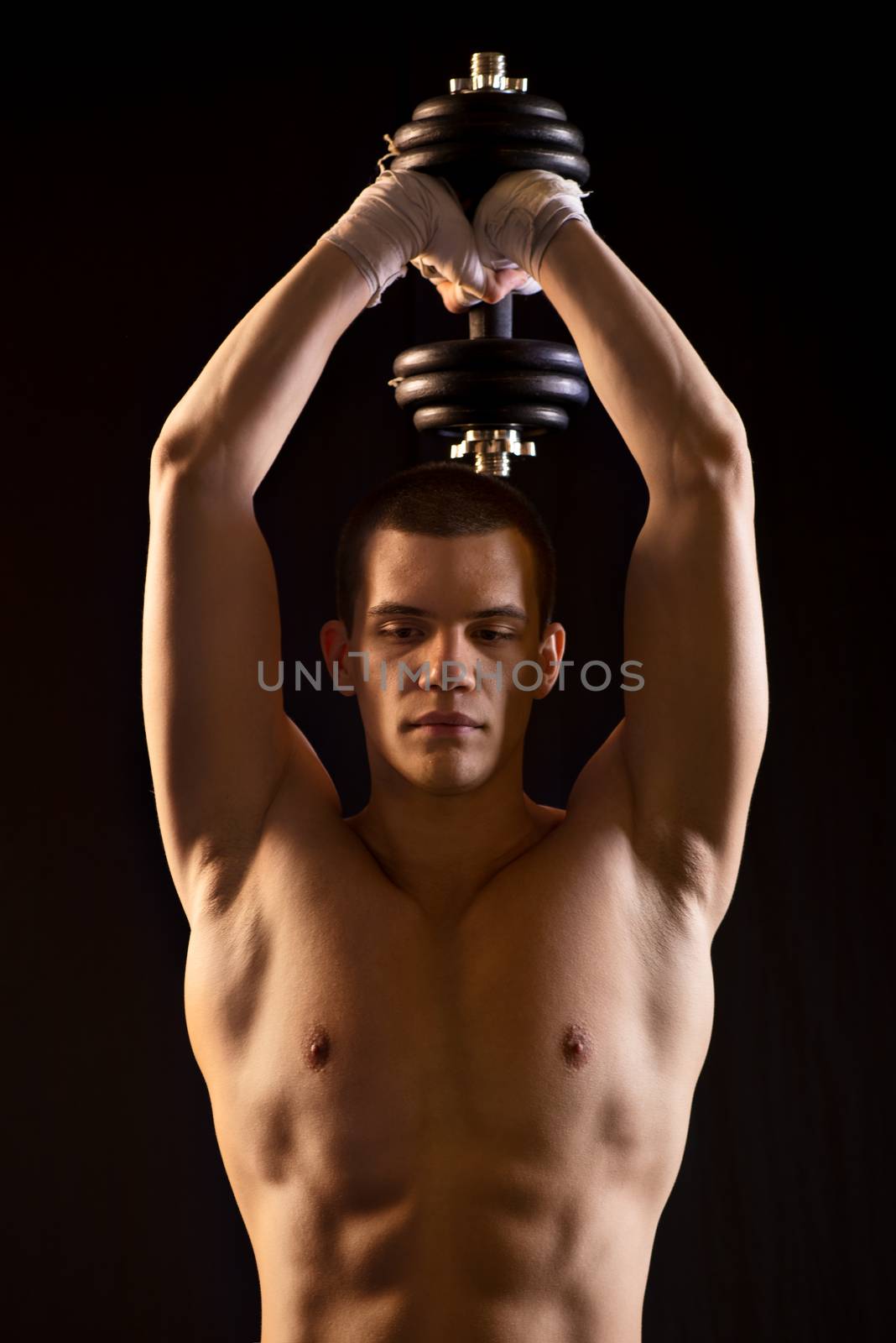 Young man doing exercises to strengthen his triceps with dumbbells.