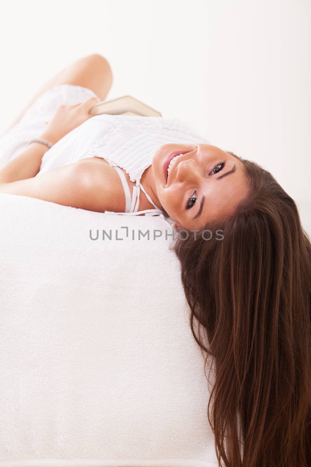 Beautiful young woman lying on bed and smiling.