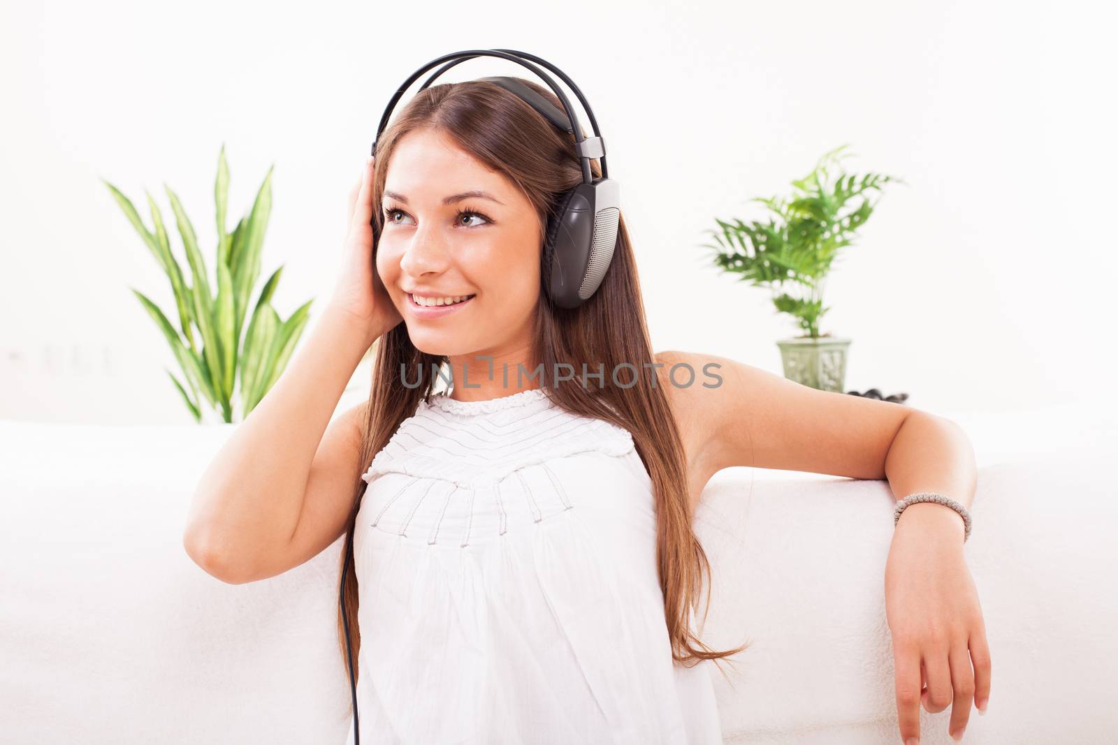 Beautiful young woman sitting at the room and listening music.