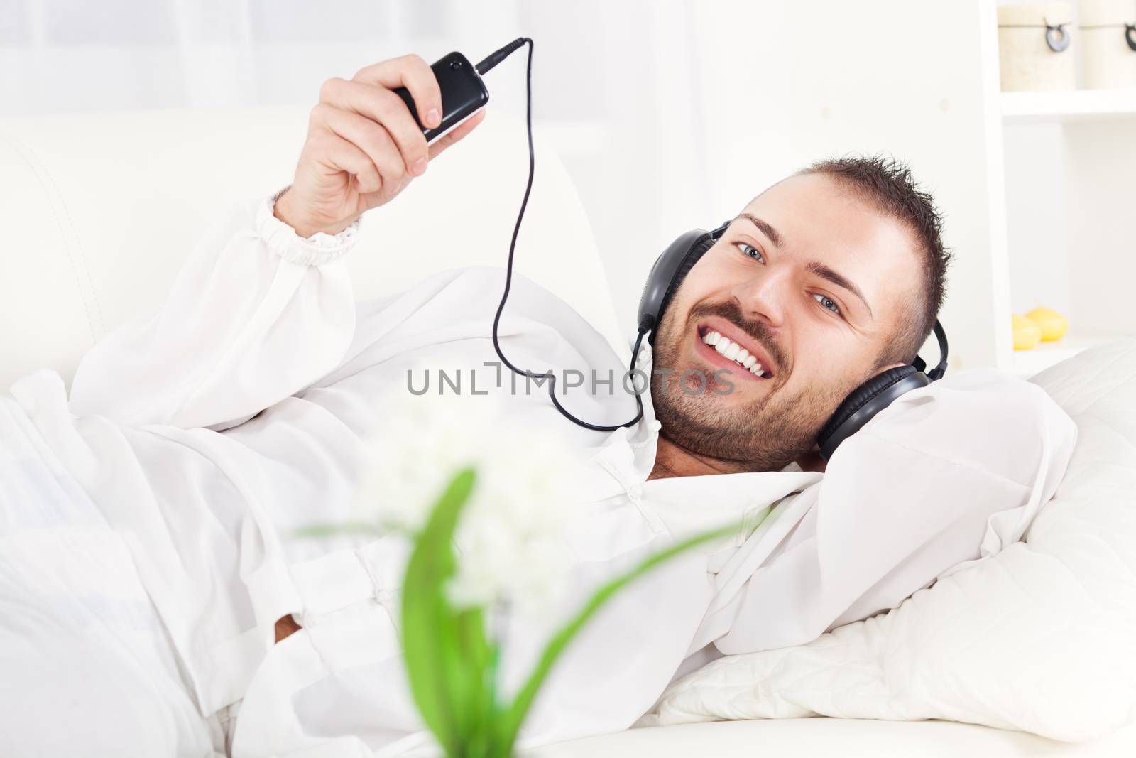 Beautiful young man resting and listening music at home.