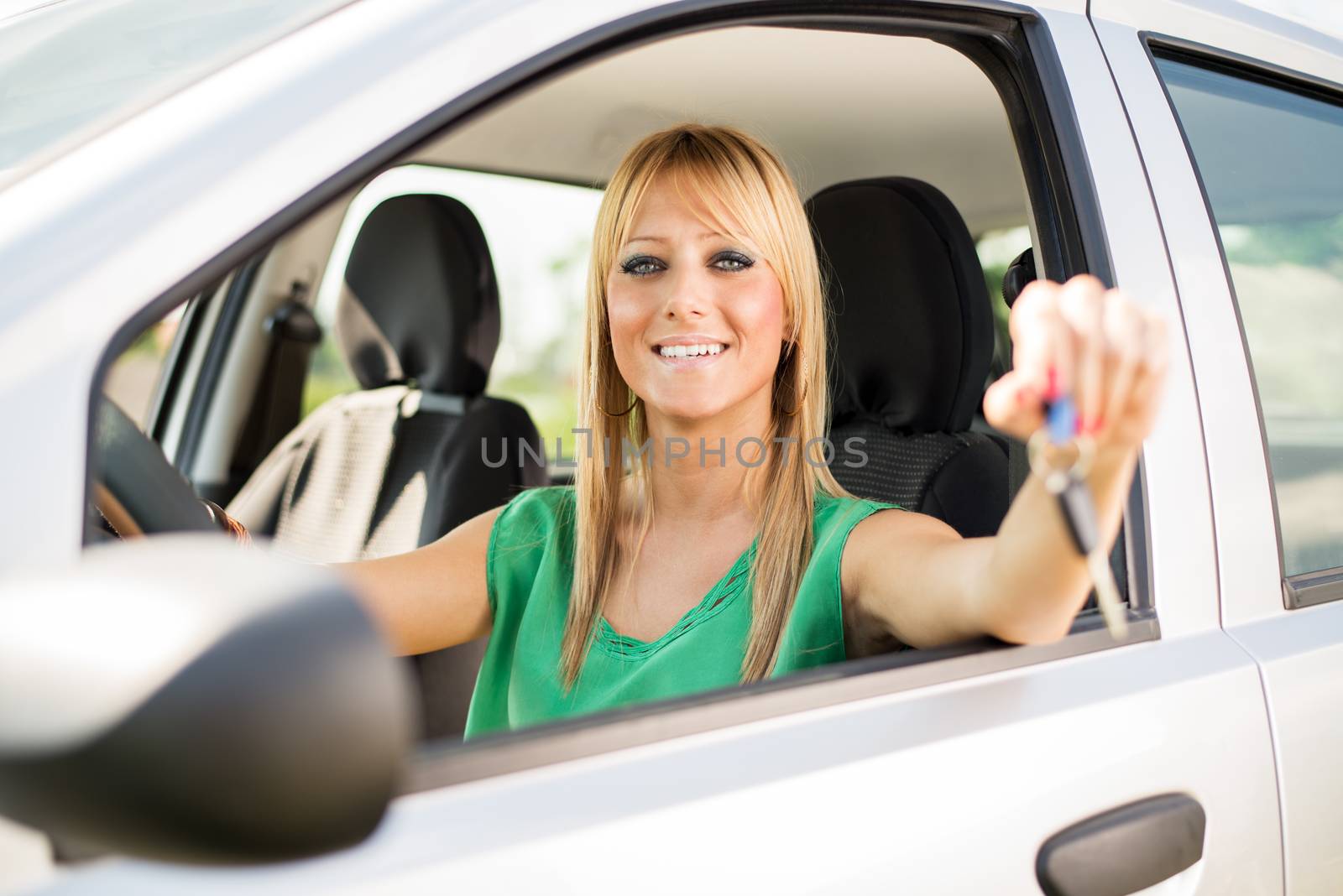 Smiling woman sitting in new car, and holding the keys.