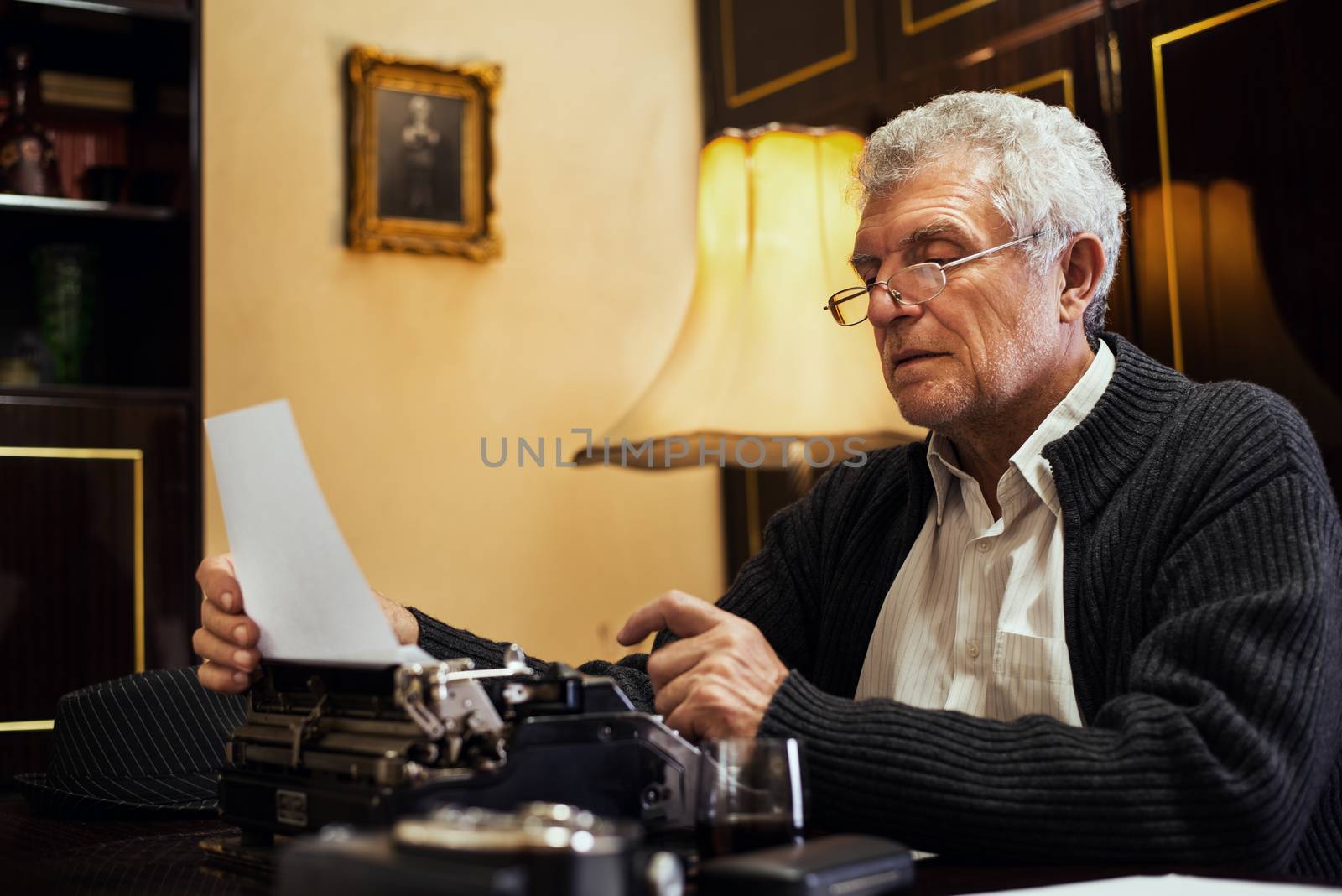 Retro Senior man writer with glasses writing on Obsolete Typewriter.