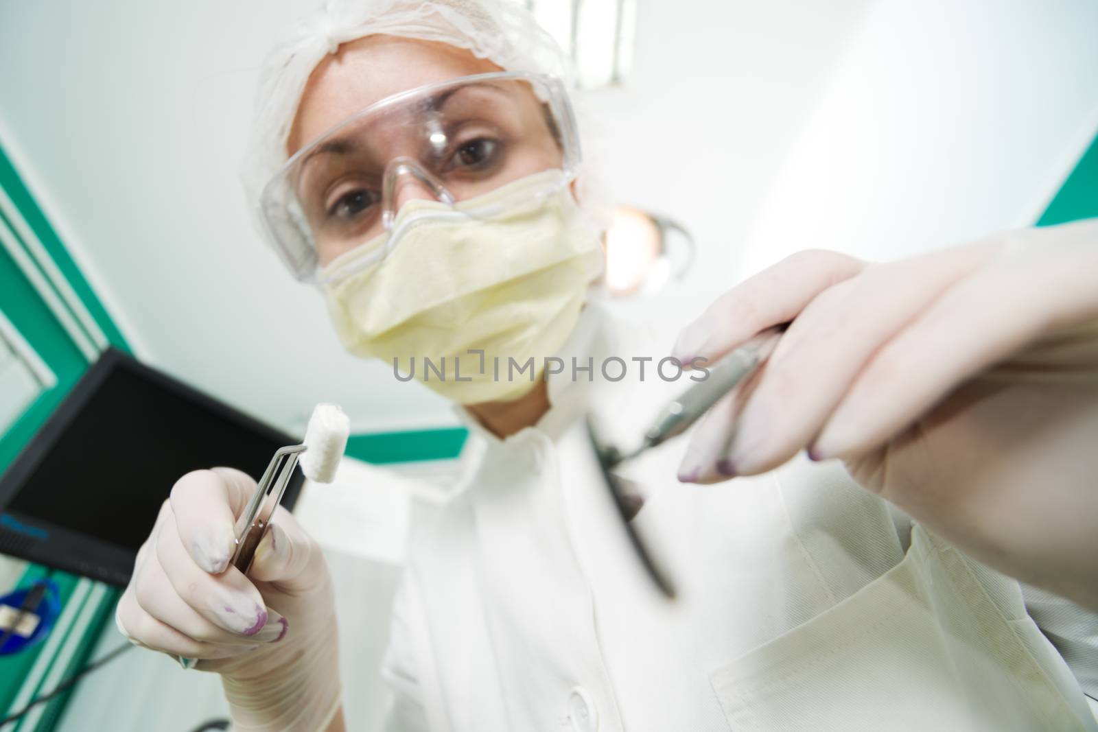 Dentist holding Dental Tweezers with coton pad and Angled Mirror for inspecting a patient. Selective Focus.