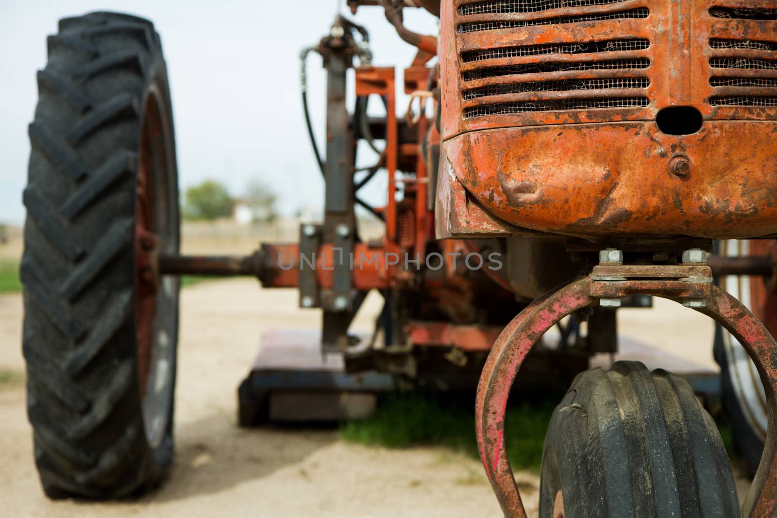 Showing the front radiator and part of the tire of an old time rusted out tractor