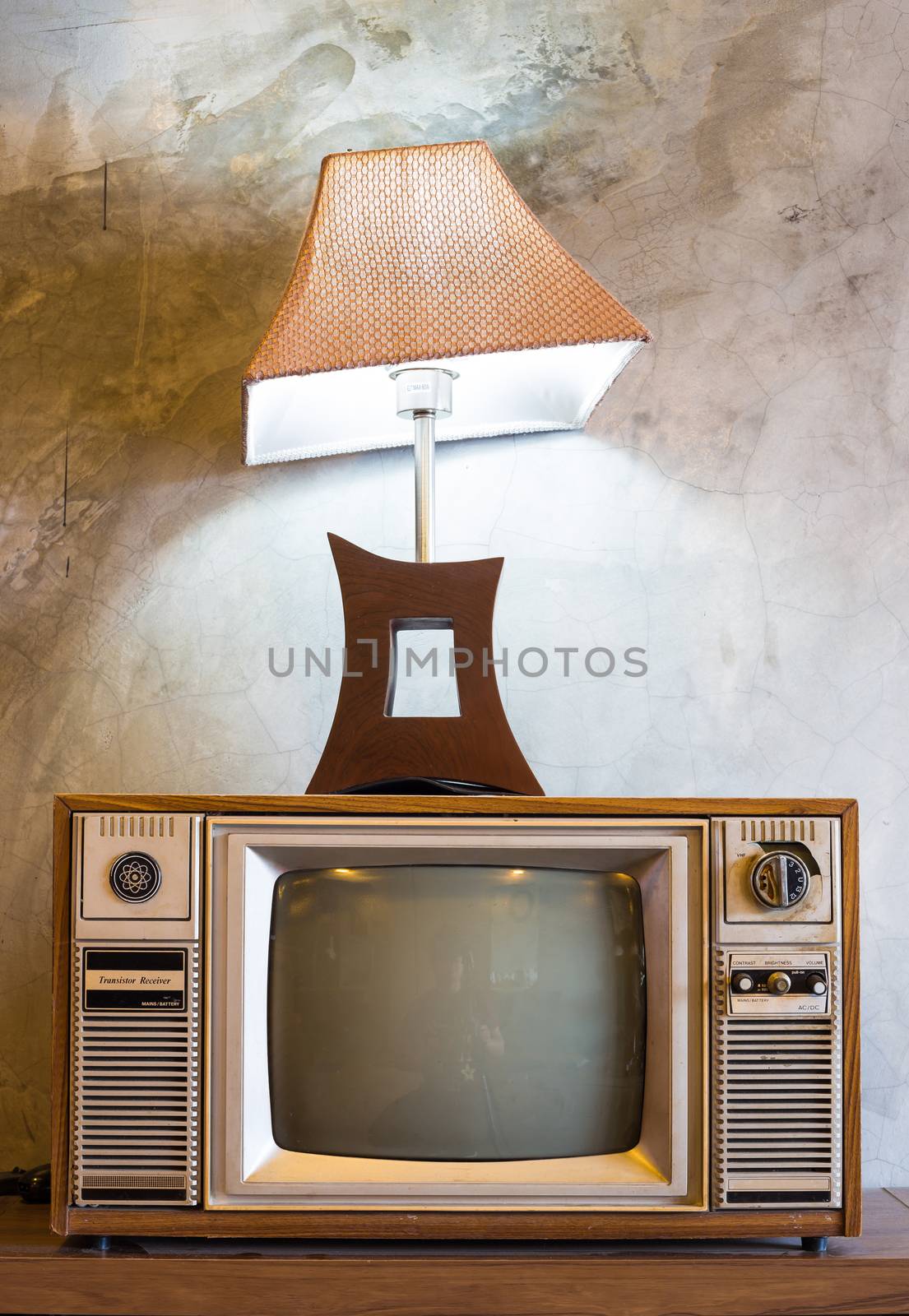 retro tv with wooden case and lantern in room with vintage wallpaper on wood table
