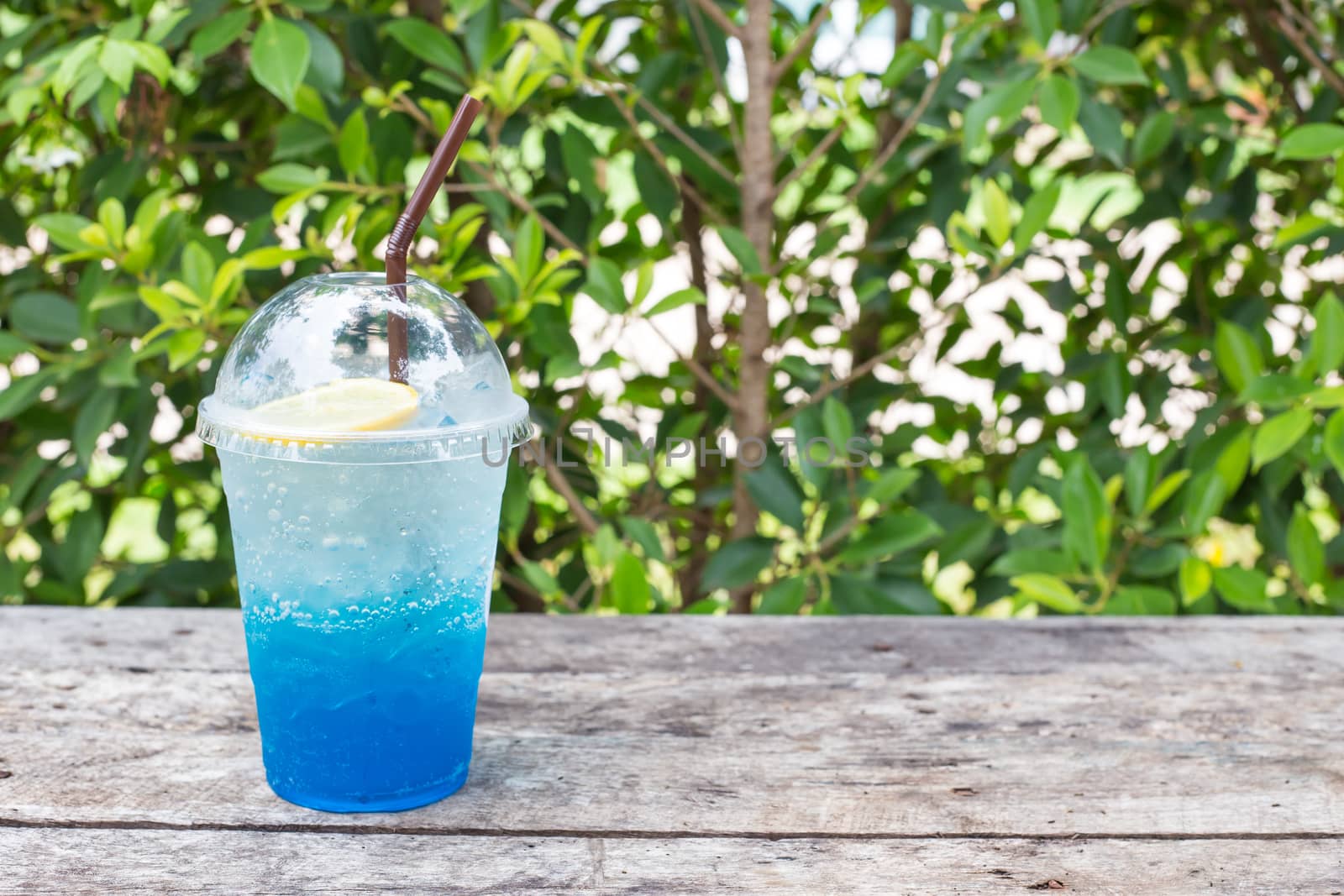 blue lemon soda on wood table with green leaves background, be fresh in nature