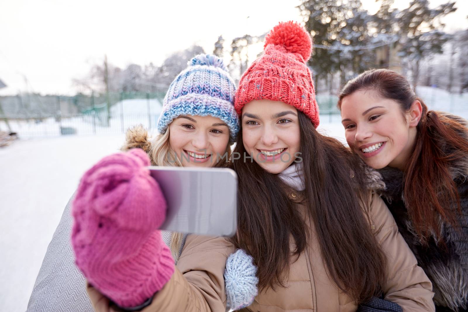 people, friendship, technology, winter and leisure concept - happy teenage girls taking selfie with smartphone outdoors
