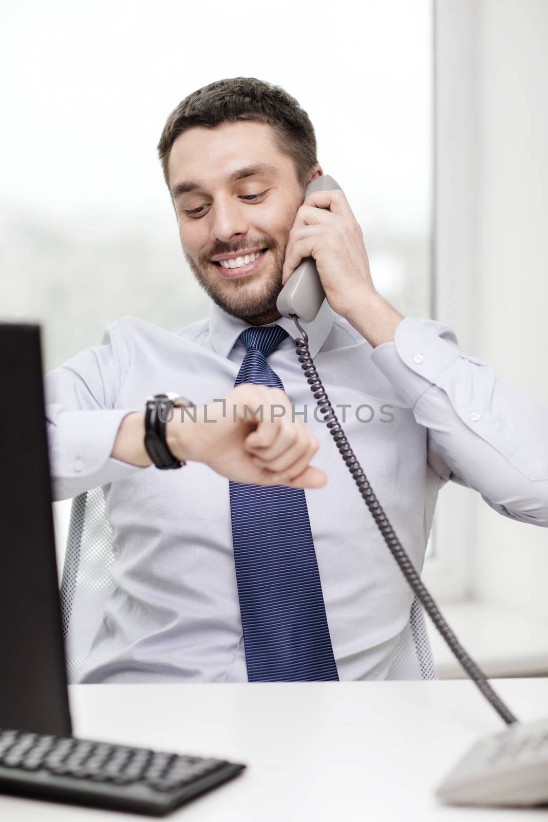 business, office and technology concept - smiling businessman making call and looking at wristwatch at office