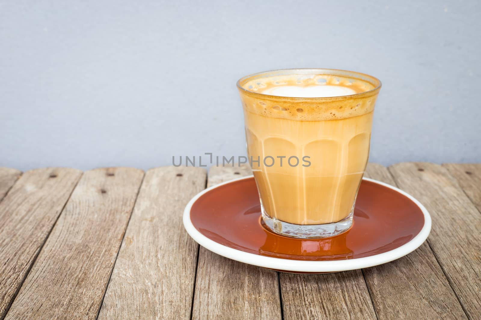 latte art coffee in glass clear cup on wood table by powerbeephoto