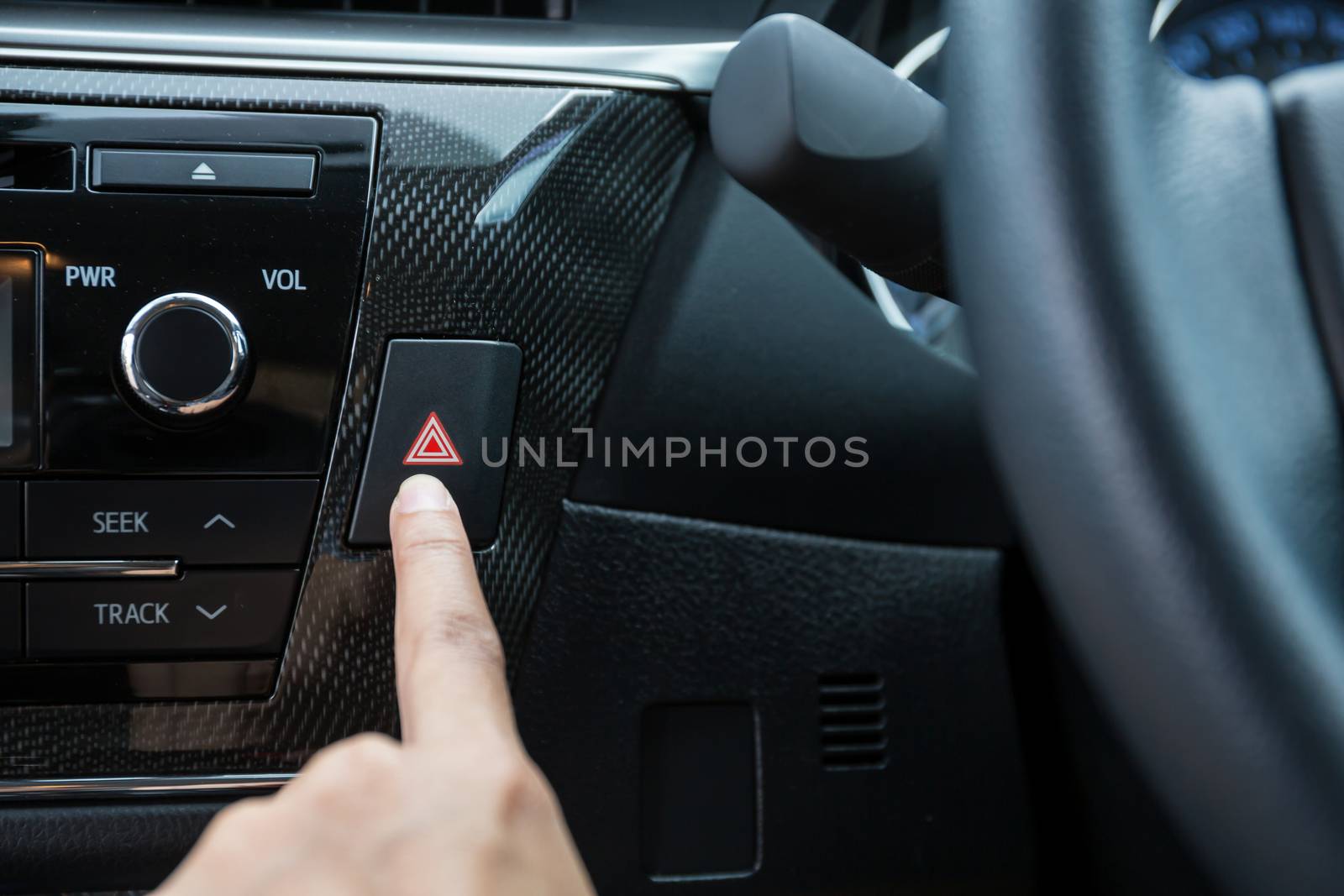 Closeup of young woman pressing emergency button on car sport dashboard.