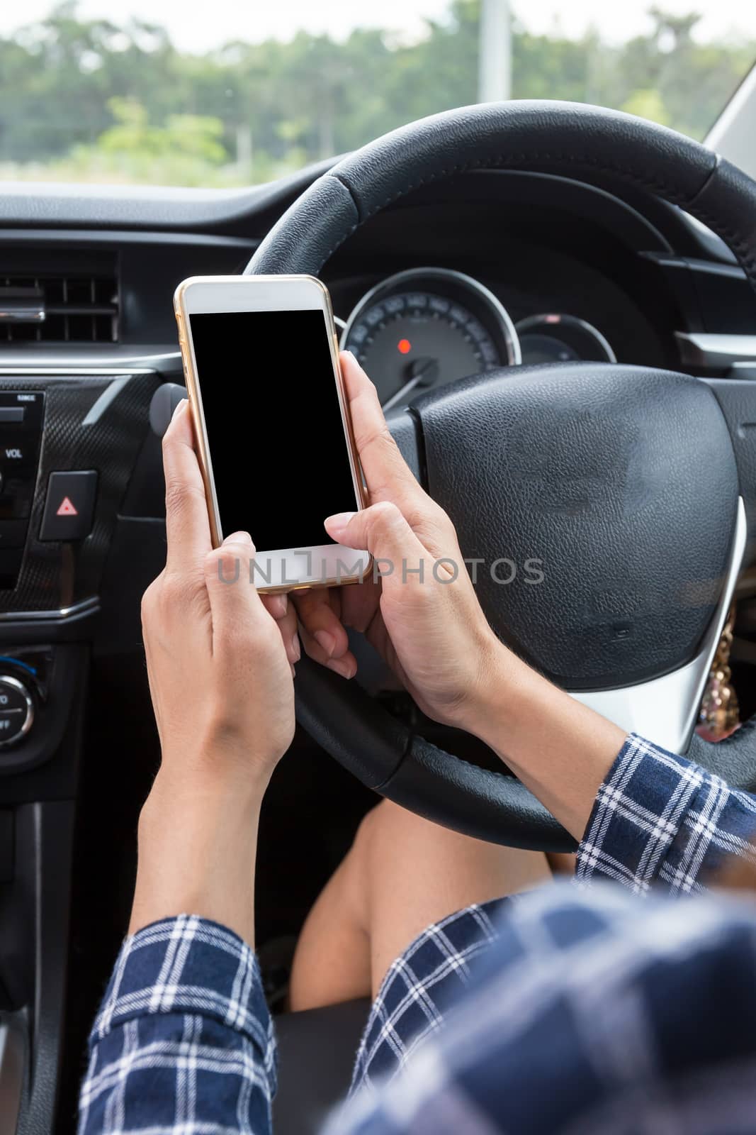 Young female driver using touch screen smartphone in a car.