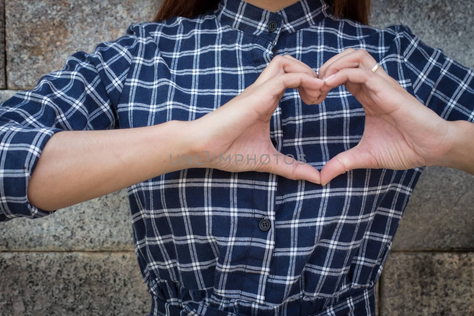 Woman holds heart shape on own. Love emotion (focus shirt)