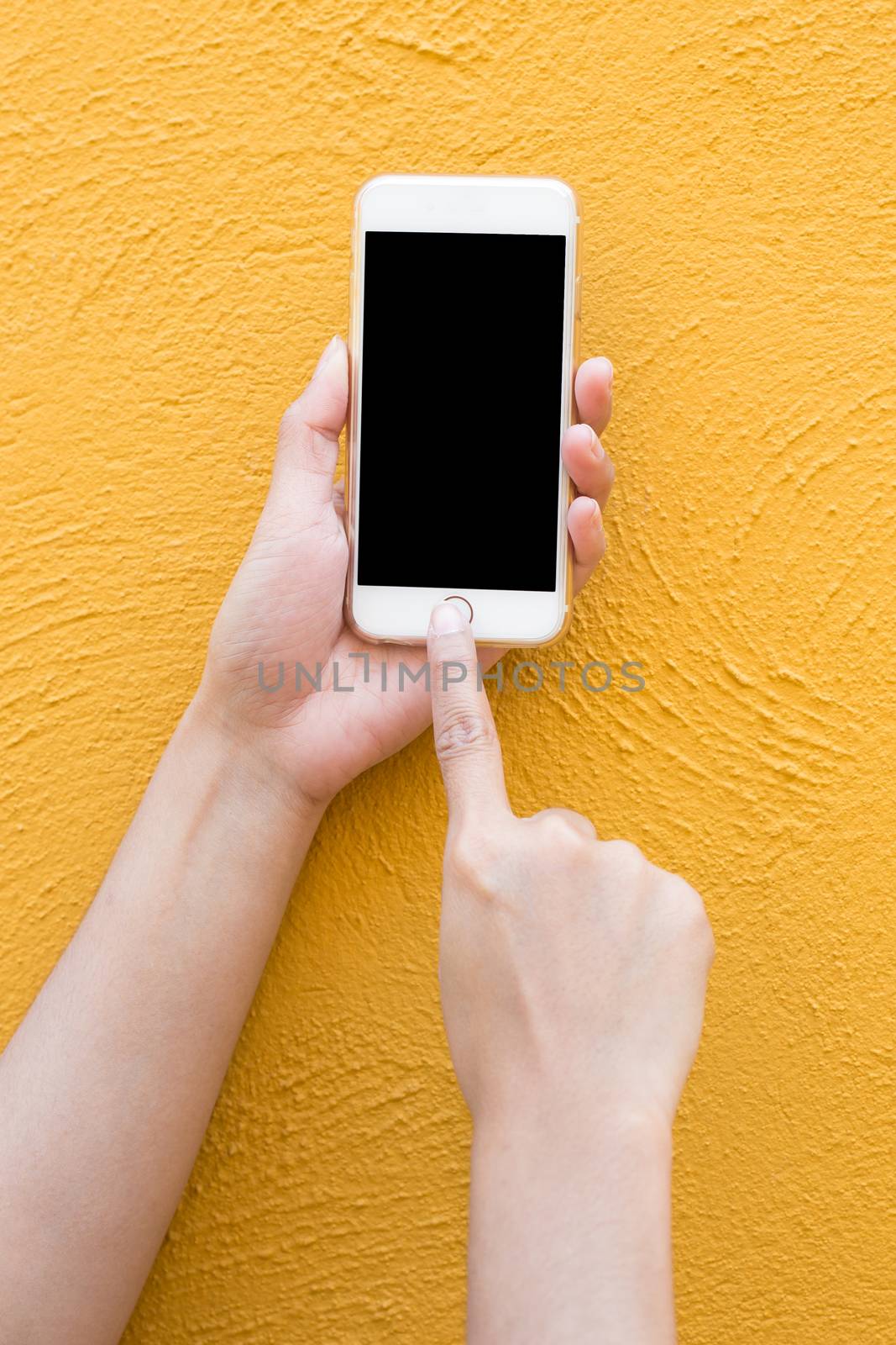 Hand holding white Smartphone on yellow wall background