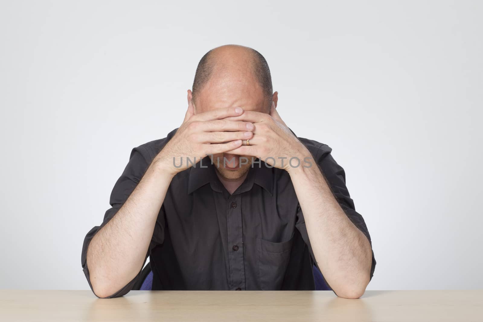 stressed man looking down at desk