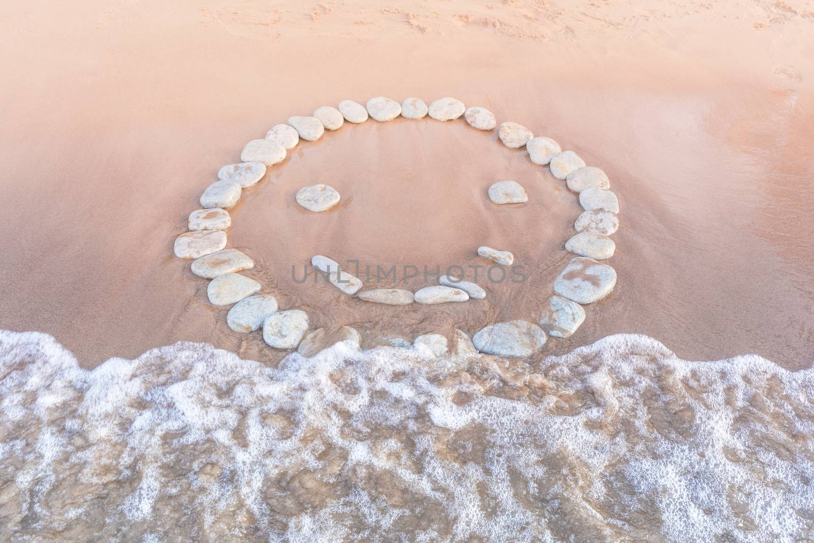 Emoticon of pebbles on the sandy beach