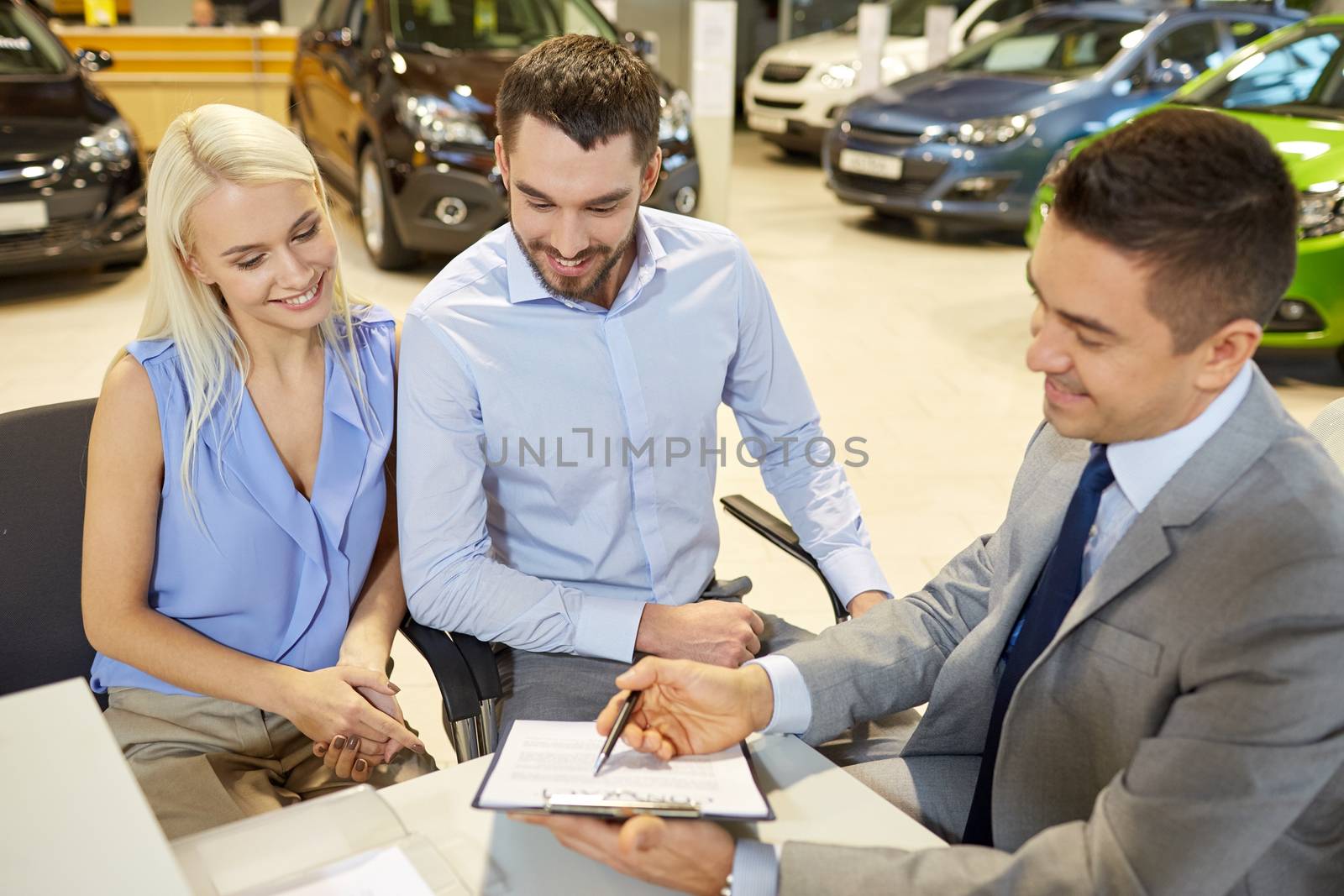 auto business, sale and people concept - happy couple with dealer buying car in auto show or salon