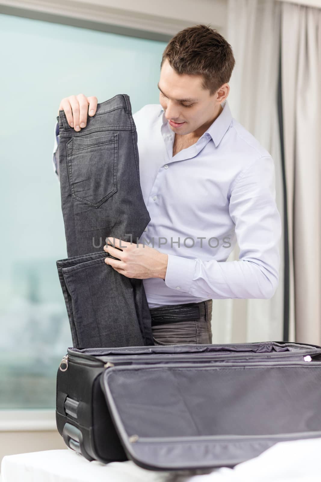 businessman packing things in suitcase by dolgachov