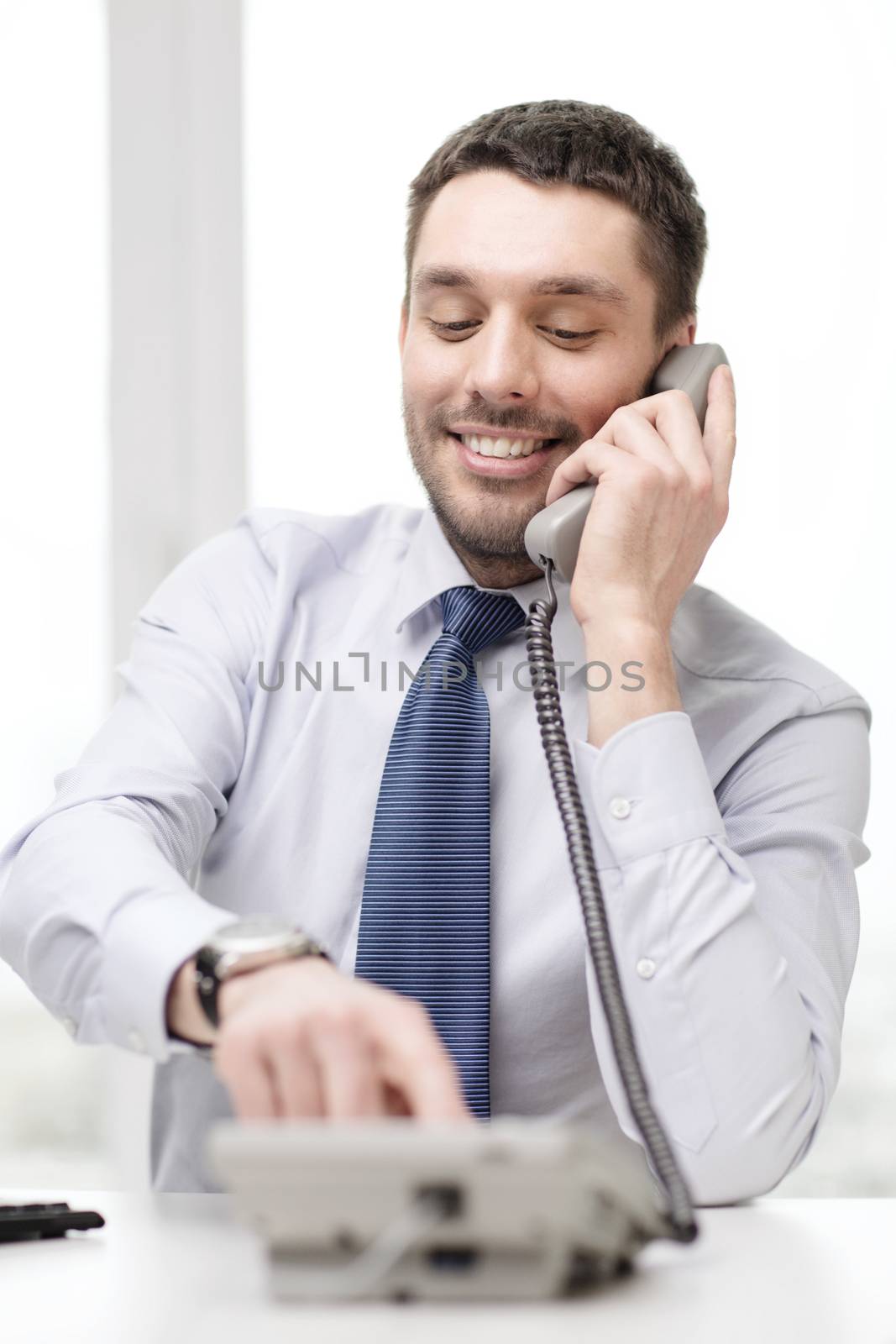 smiling businessman with telephone dialing number by dolgachov