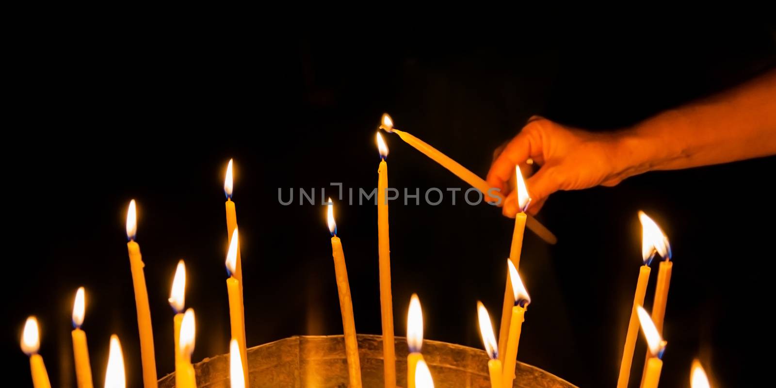 man lights a candle in the church of the Holy Sepulchre in Jerusalem