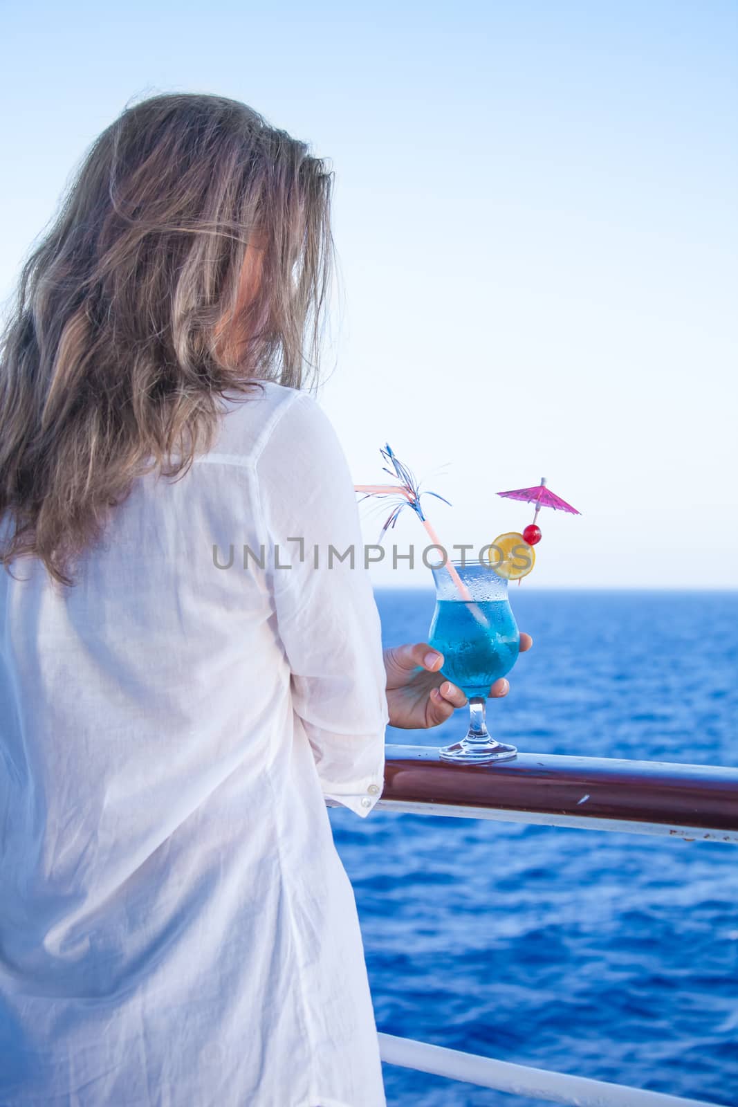 pretty girl with a cold drink, admiring the sea views summer