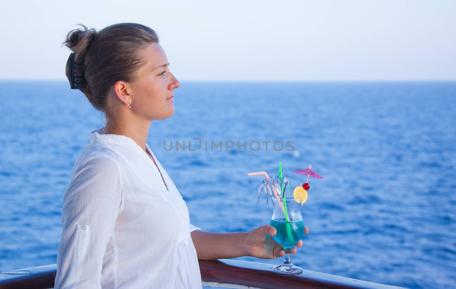 pretty girl drinking a cold drink, admiring the sea views summer