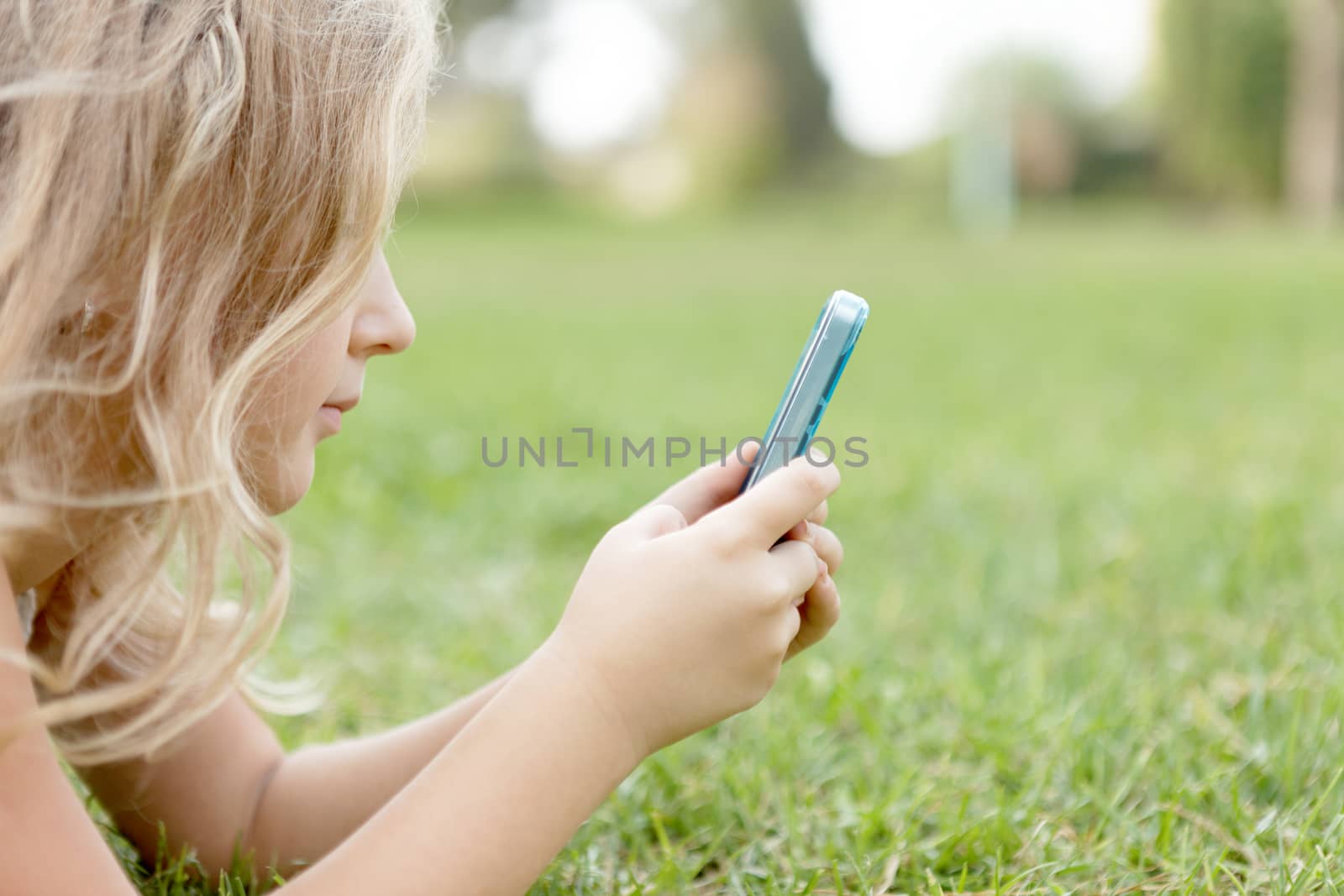 blond baby girl outdoors with a mobile phone