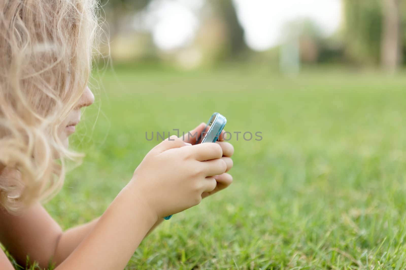 Girl With mobiles resting on the grass in the park