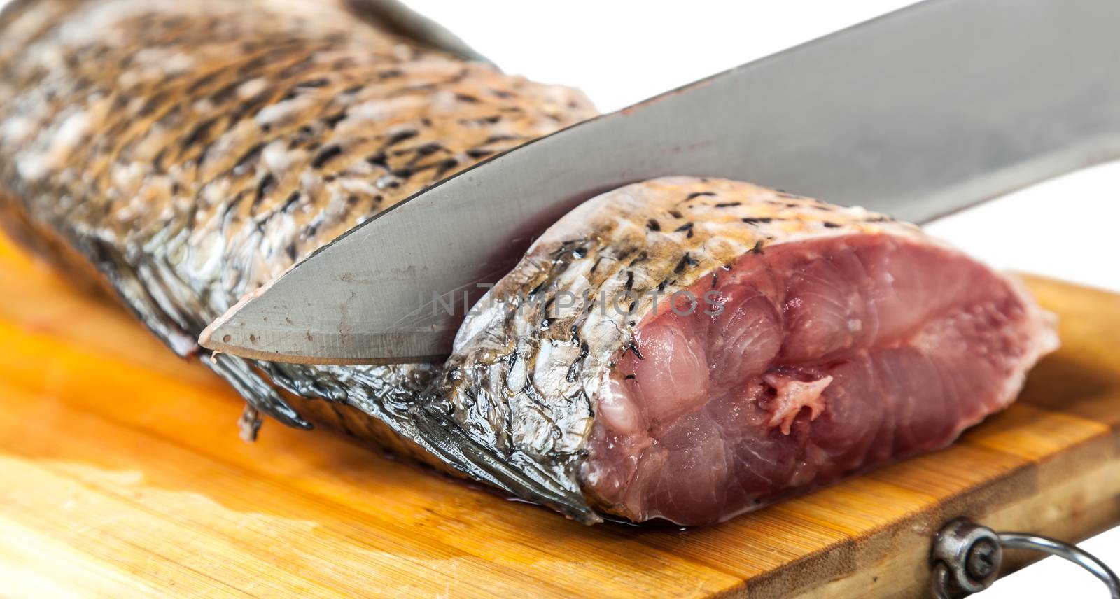 part of the fish lying on the kitchen board with knife