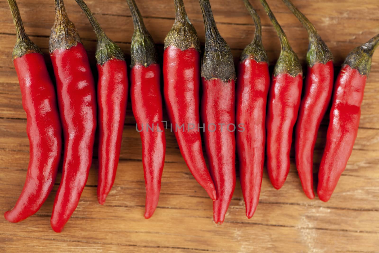 red chilli lying in a row on a wooden background