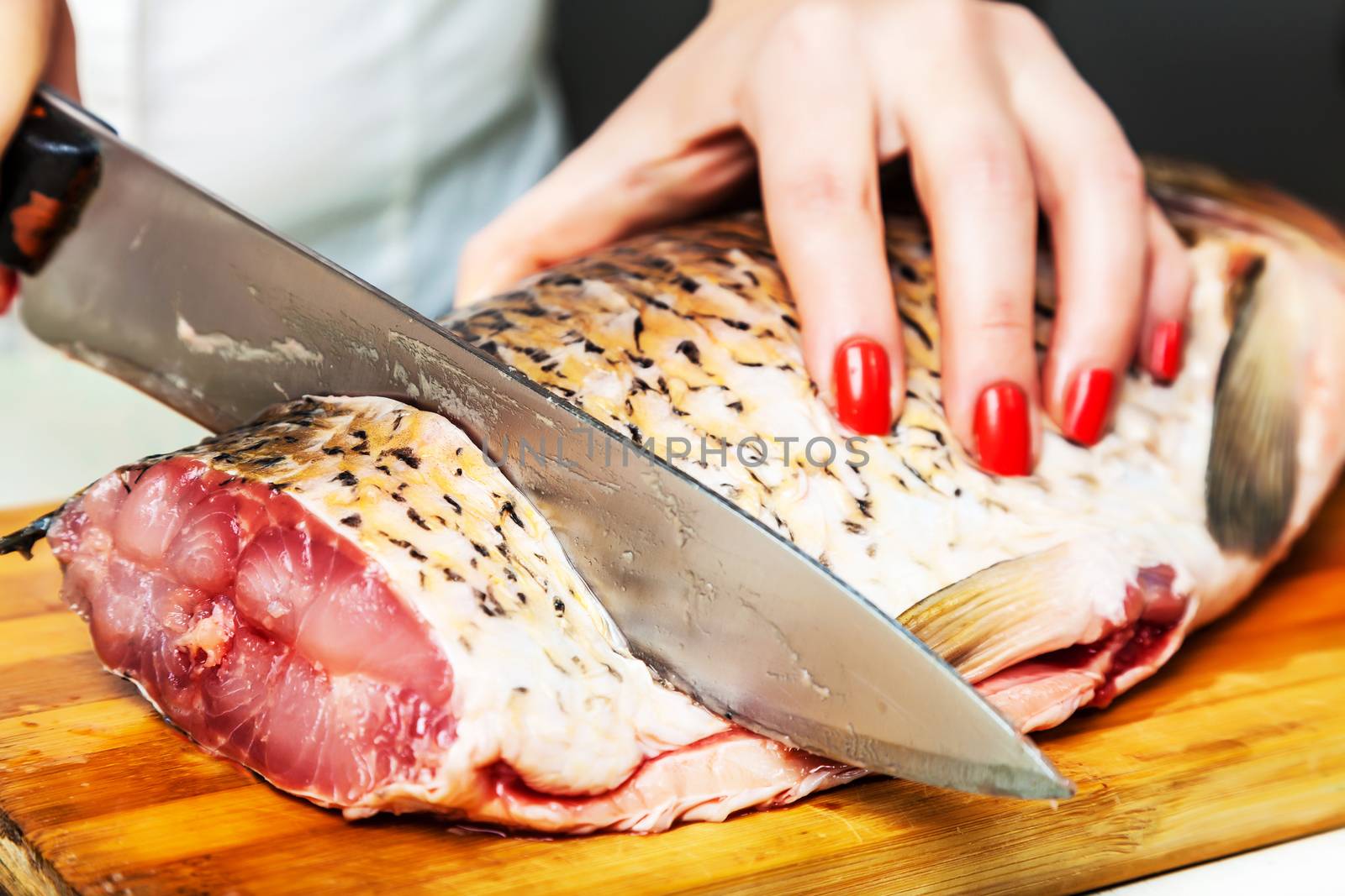 girl with a kitchen knife cut the fish in pieces