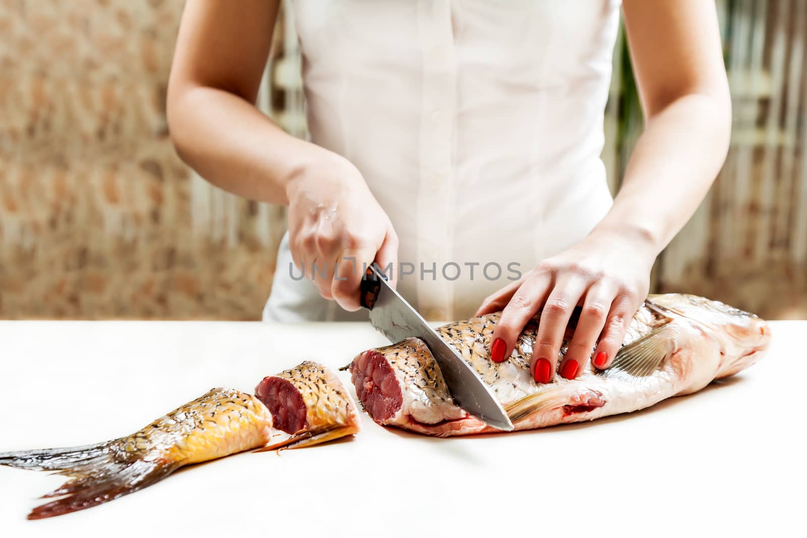 girl with a knife cut the fish into pieces of carp