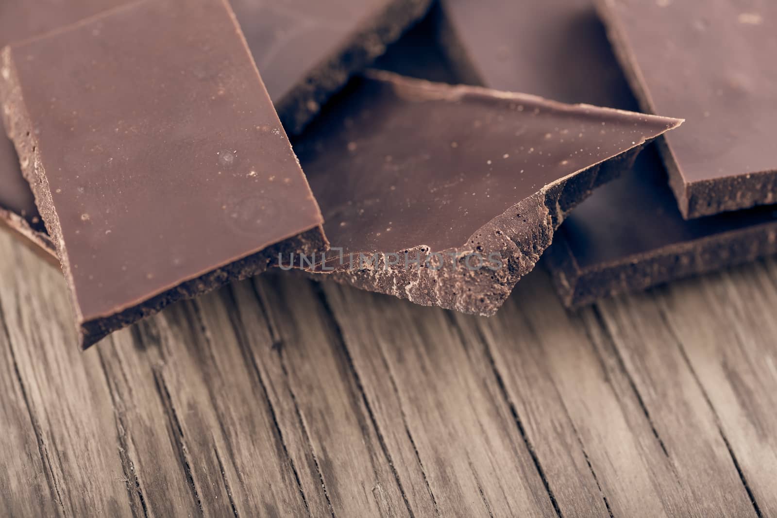 pieces of dark chocolate closeup on wooden background