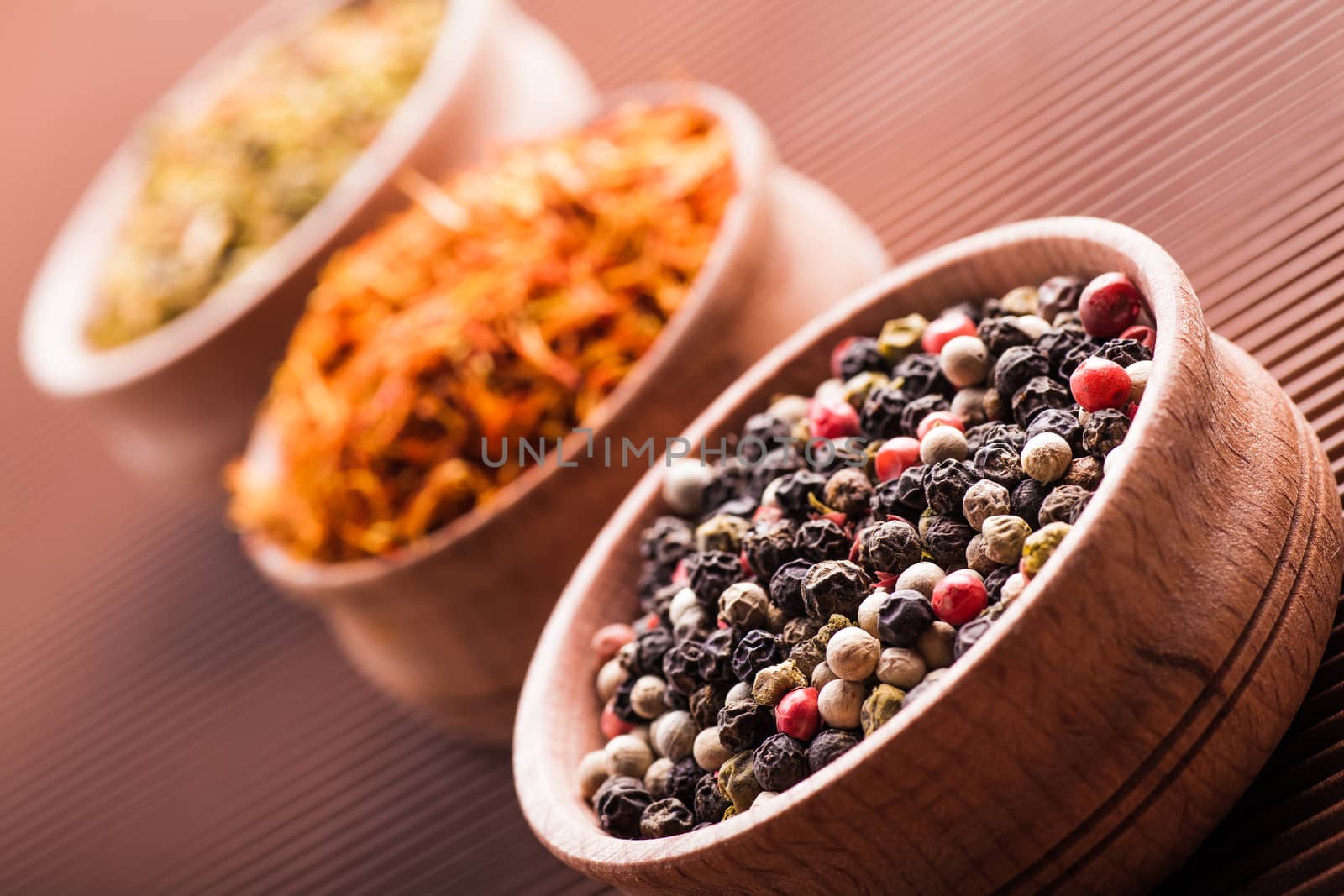 spices pepper,saffron,paprika in a wooden bowl on a brown background