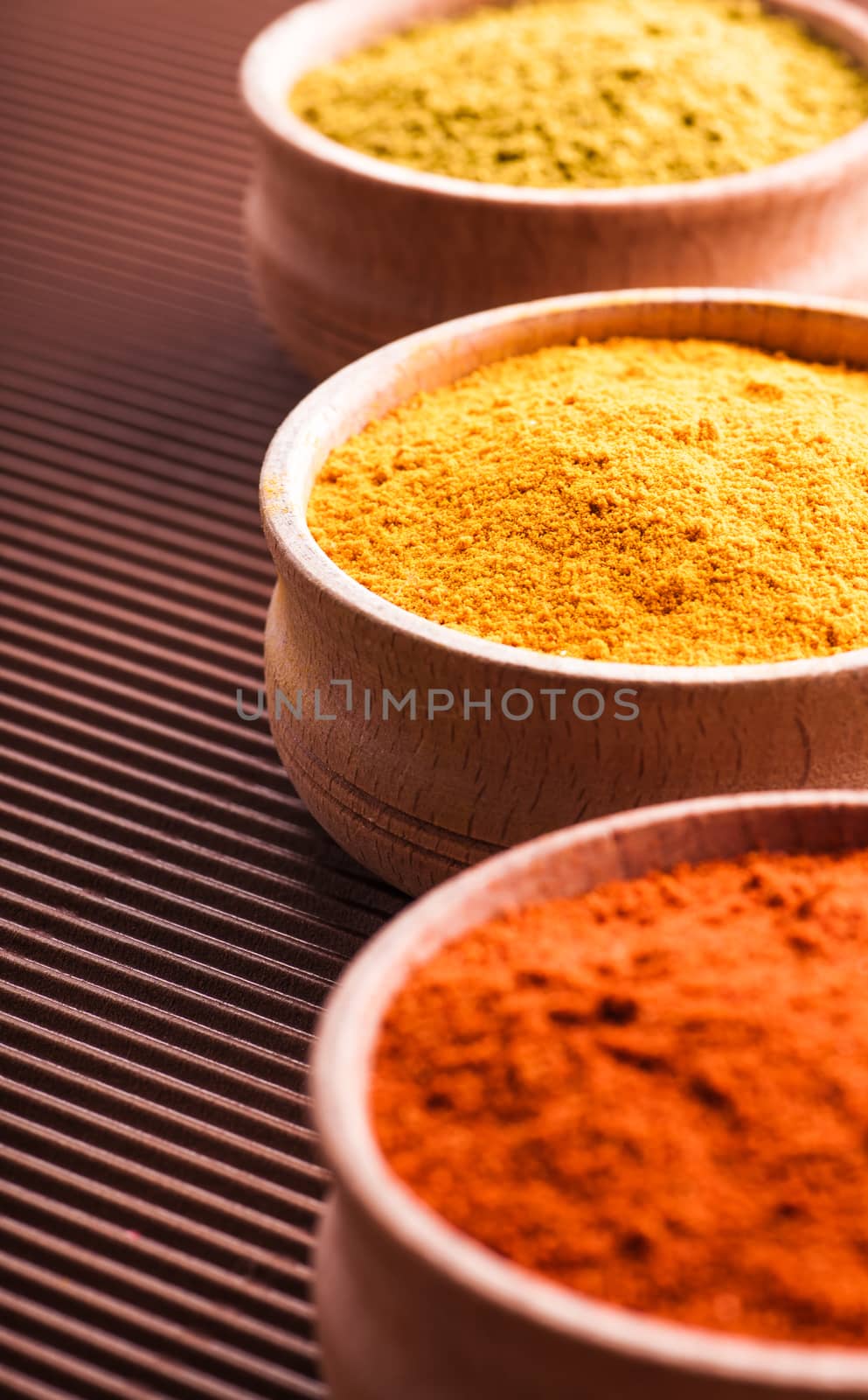 spices hops-suneli,turmeric,paprika in a wooden bowl close-up on a brown background