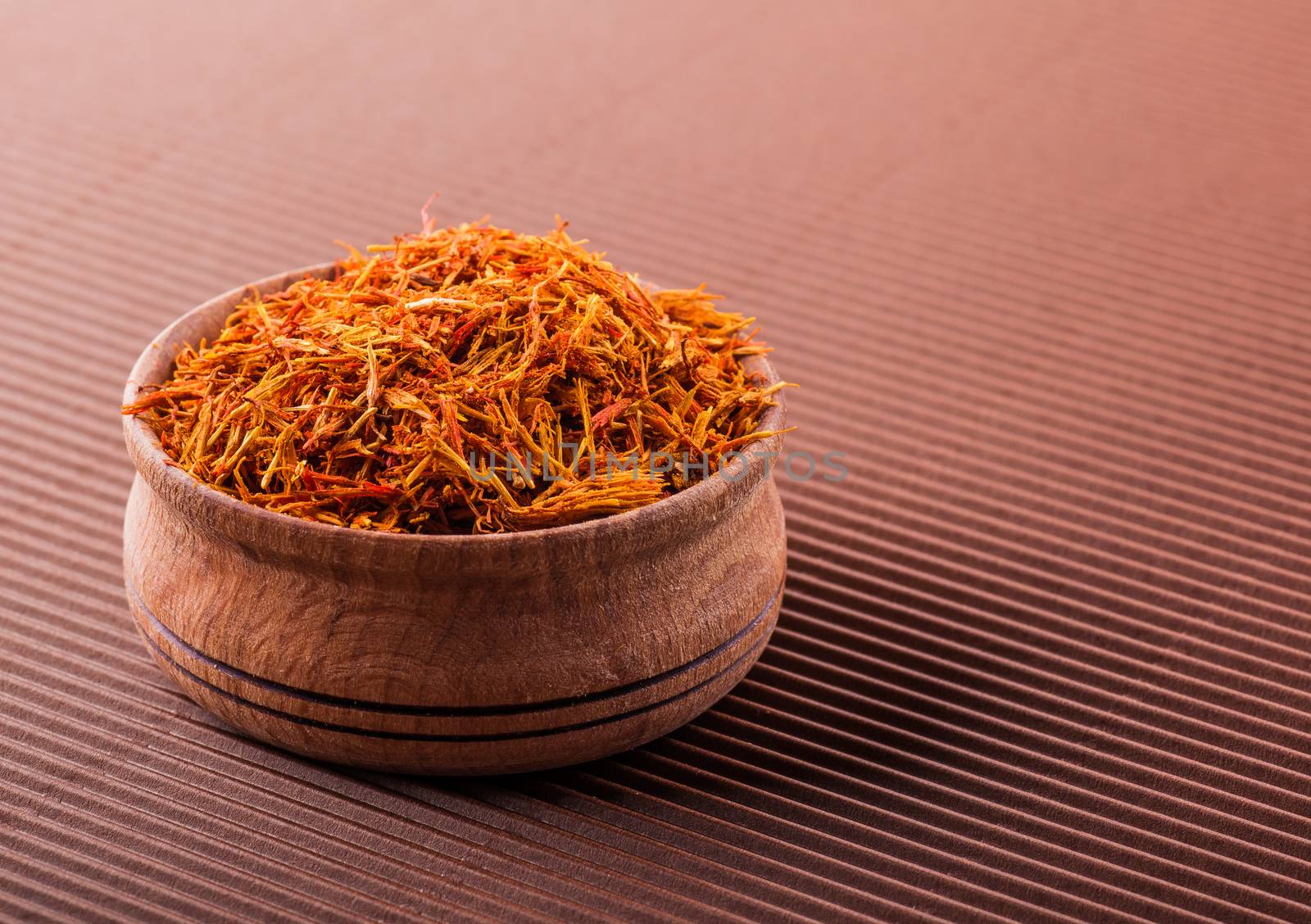 saffron in a wooden bowl on a brown background