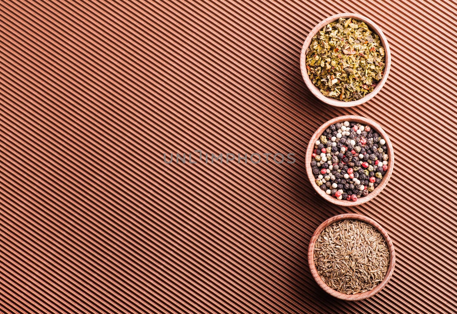 pepper,cumin,paprika in a wooden bowl on a brown background