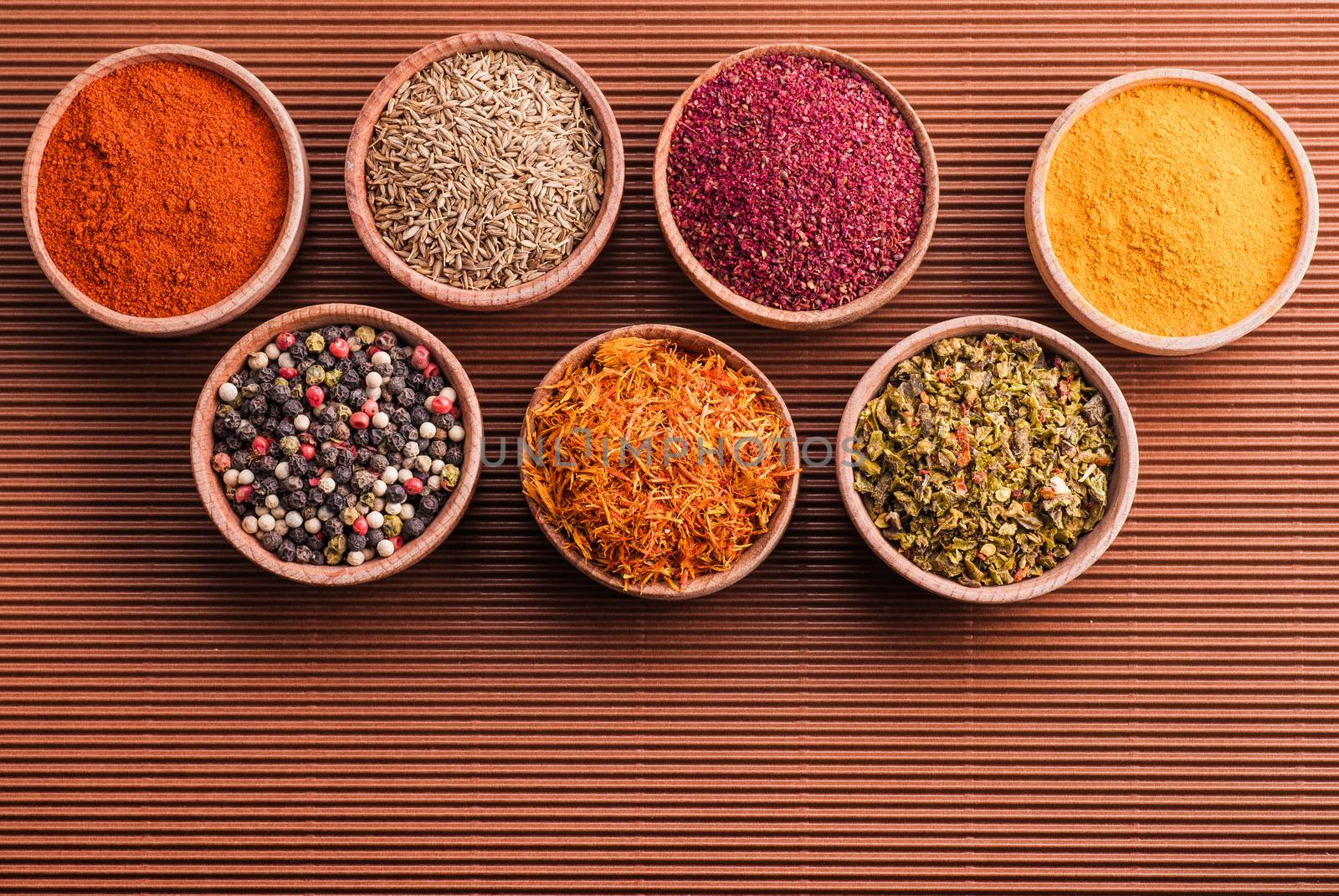 assorted spices in a wooden bowl on a brown background