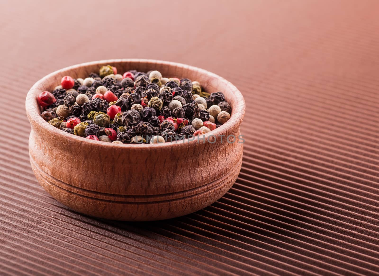 spice pepper in a wooden bowl on a brown background