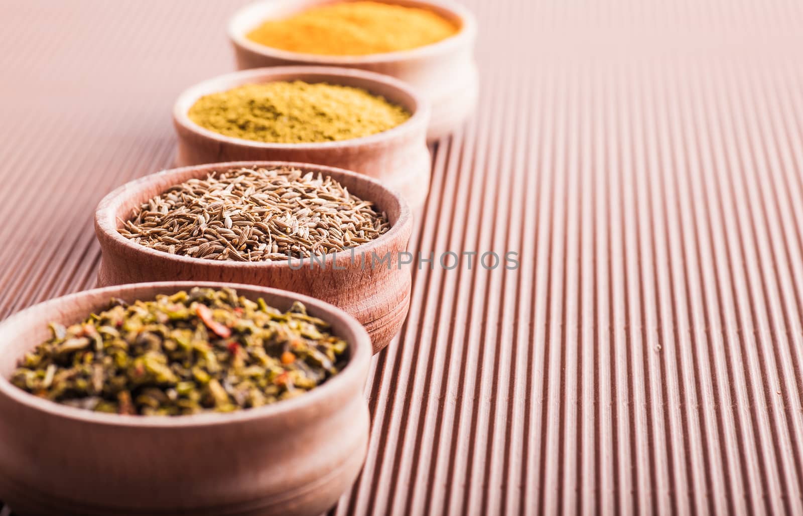 cumin,turmeric,hops-suneli,paprika in a wooden bowl on a brown background