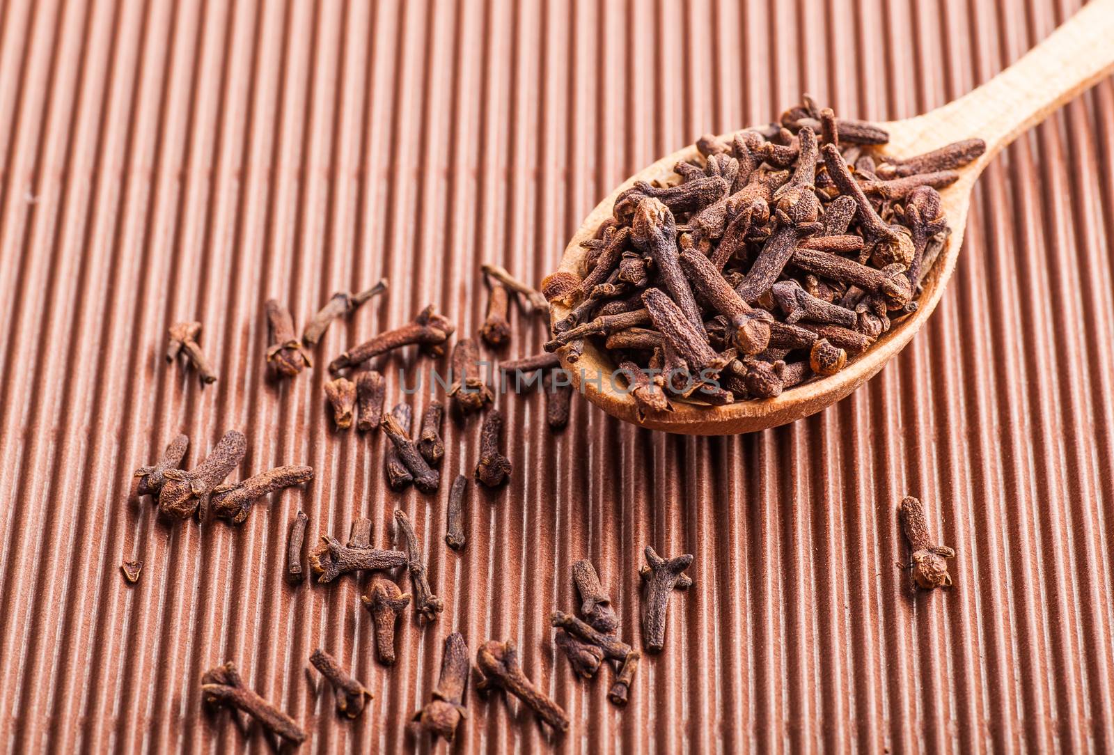 spice clove in a wooden spoon on a brown background