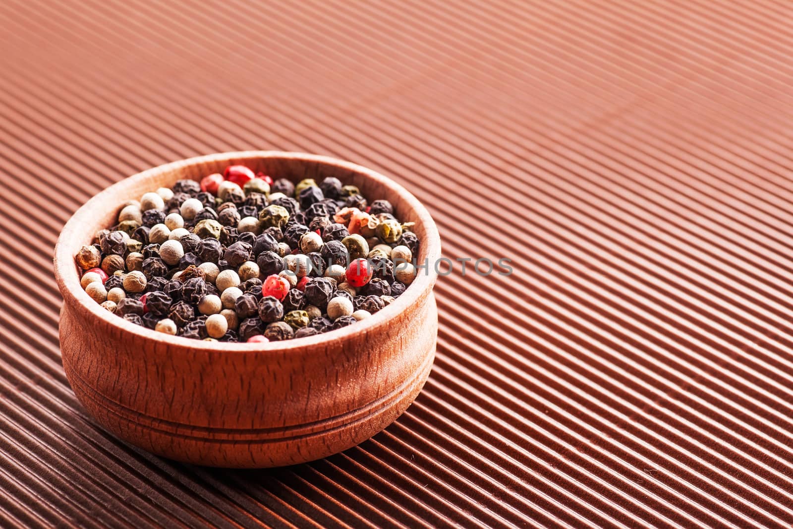 spice assorted pepper in a wooden bowl on a brown background