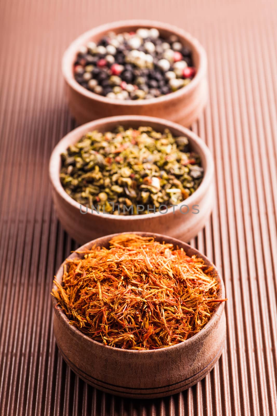 set dry spices pepper,saffron,paprika in a wooden bowl on a brown background