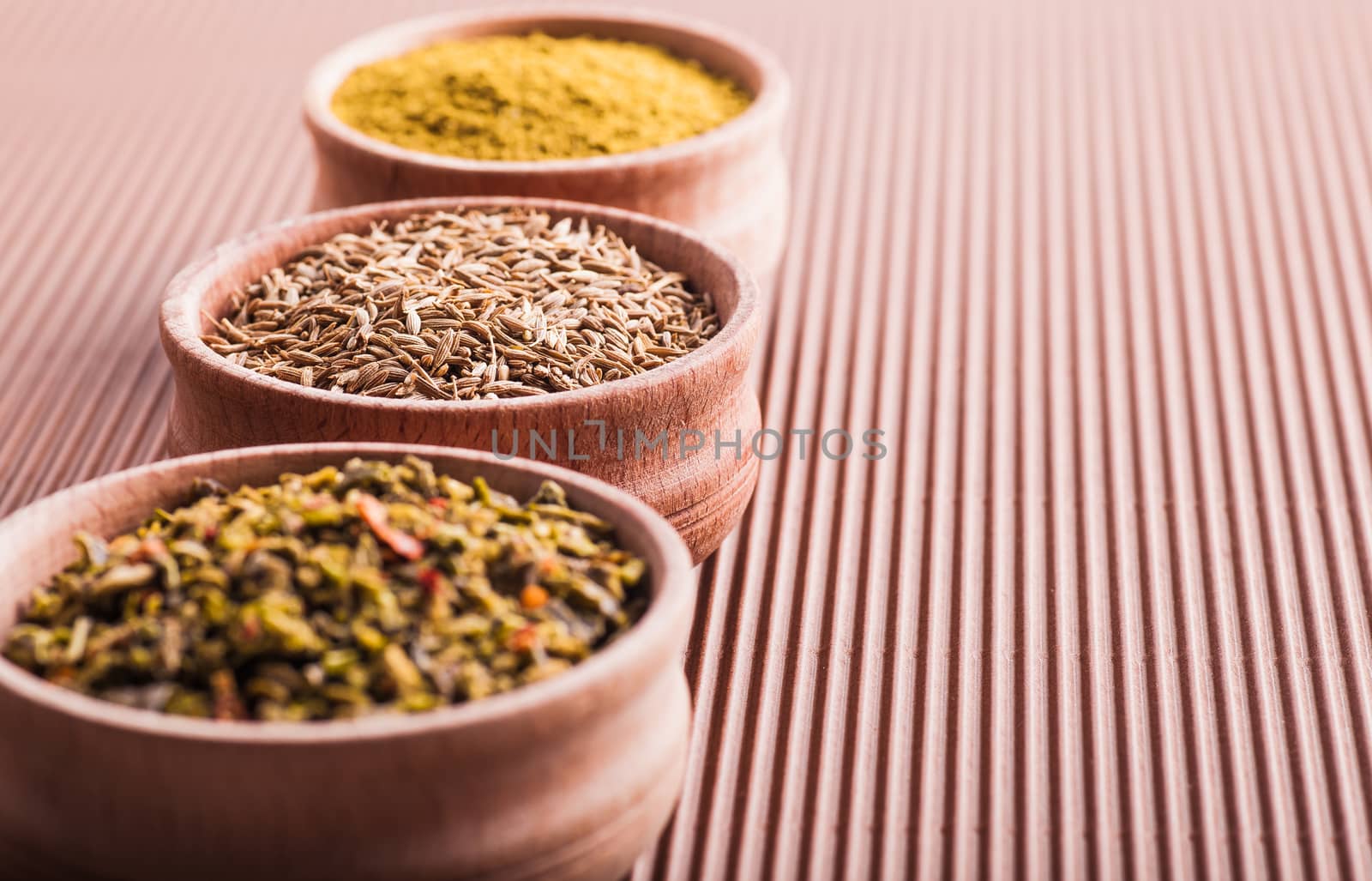 cumin,hops-suneli,paprika in a wooden bowl close-up on a brown background
