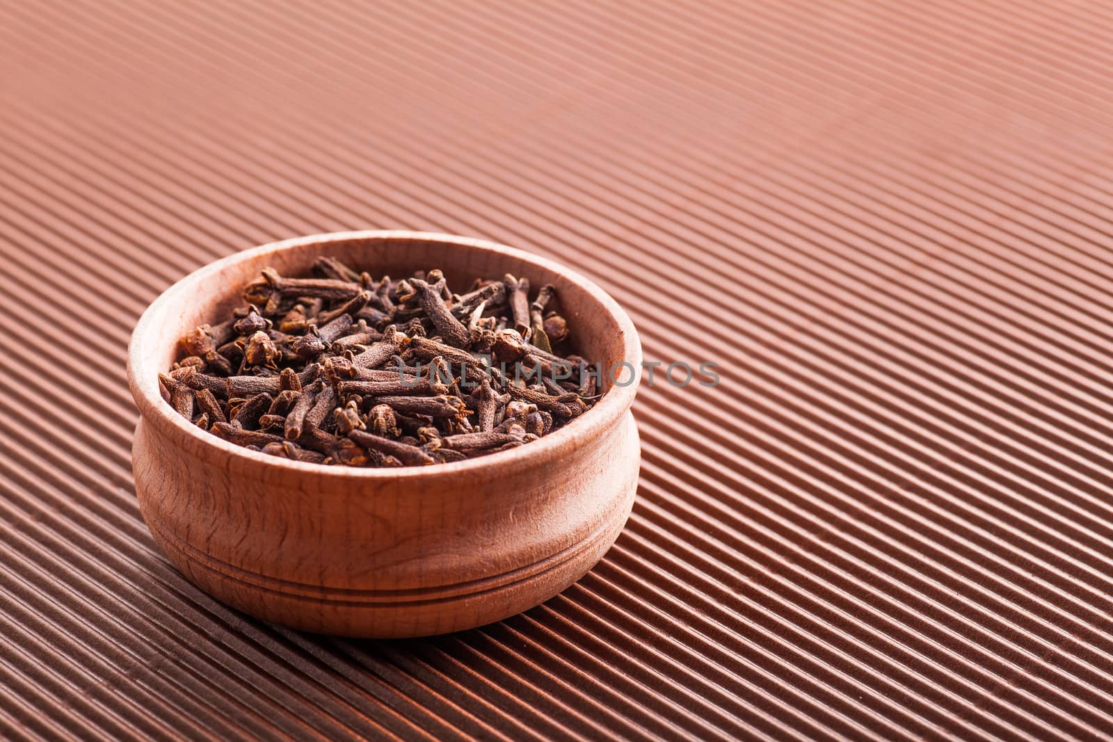 clove in a wooden bowl close-up on a brown background