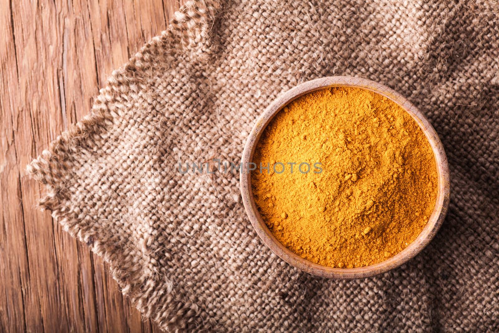 dry spice turmeric in a wooden bowl on a vintage background
