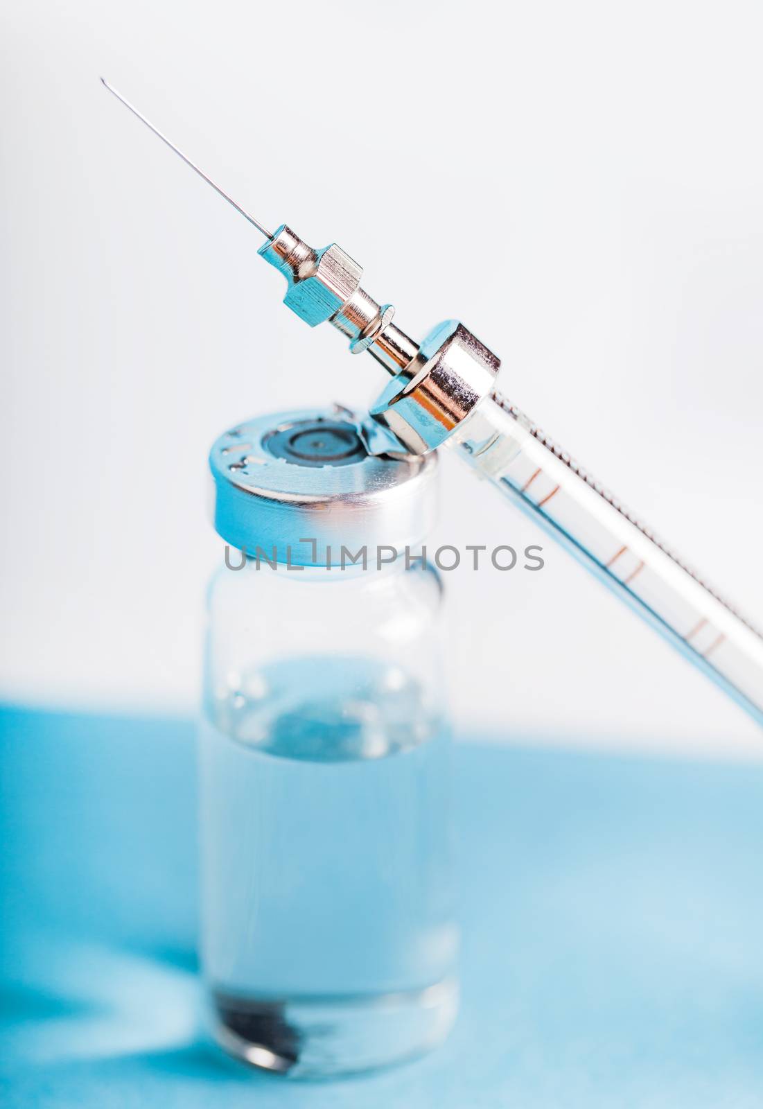 bottle of medicine and syringe on a blue background