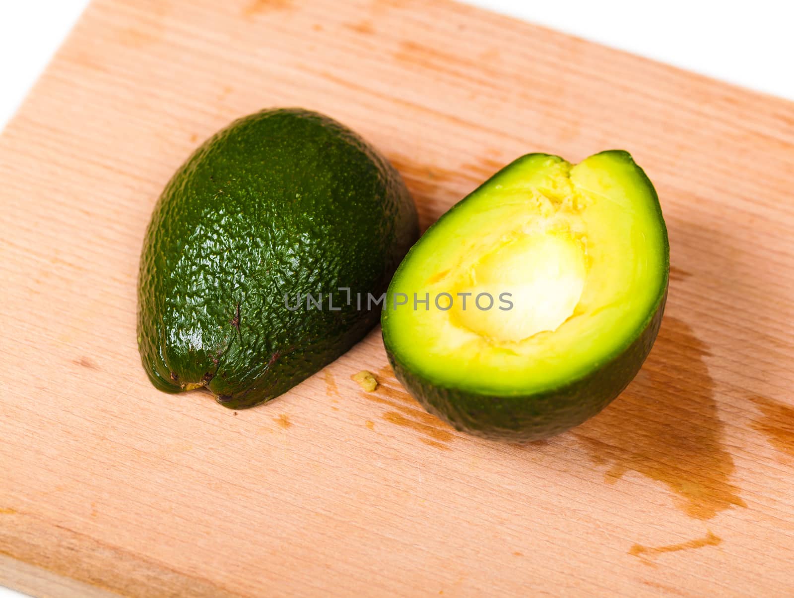 two pieces of fresh avocado close-up on a wooden board