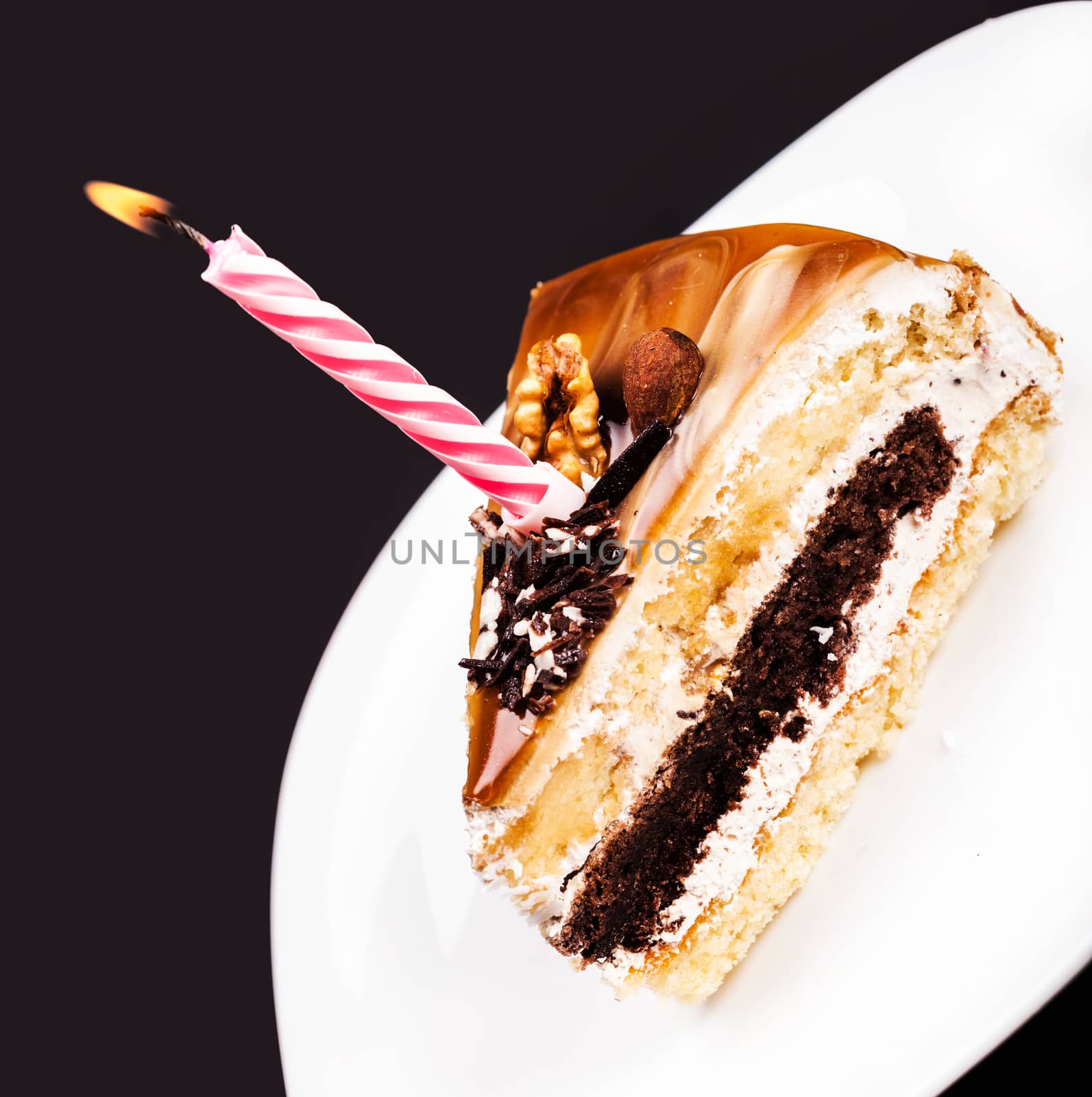 fresh piece of cake with a candle on a dark background