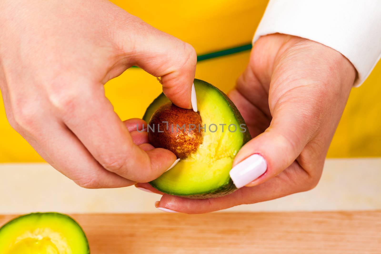 chef removes bone from fresh avocado closeup